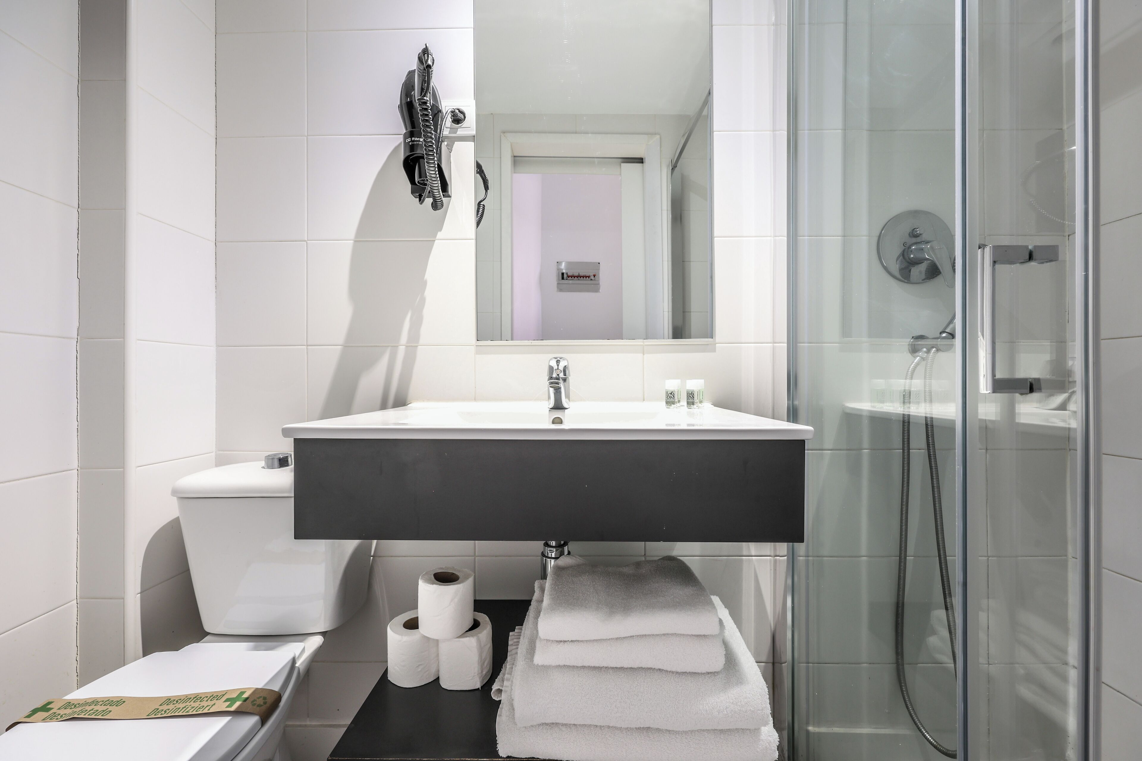 A modern bathroom with a white sink, toilet, and glass shower enclosure.