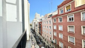 Une rue étroite bordée d’immeubles à plusieurs étages dotés de balcons, un ciel dégagé et, au loin, un gratte-ciel.