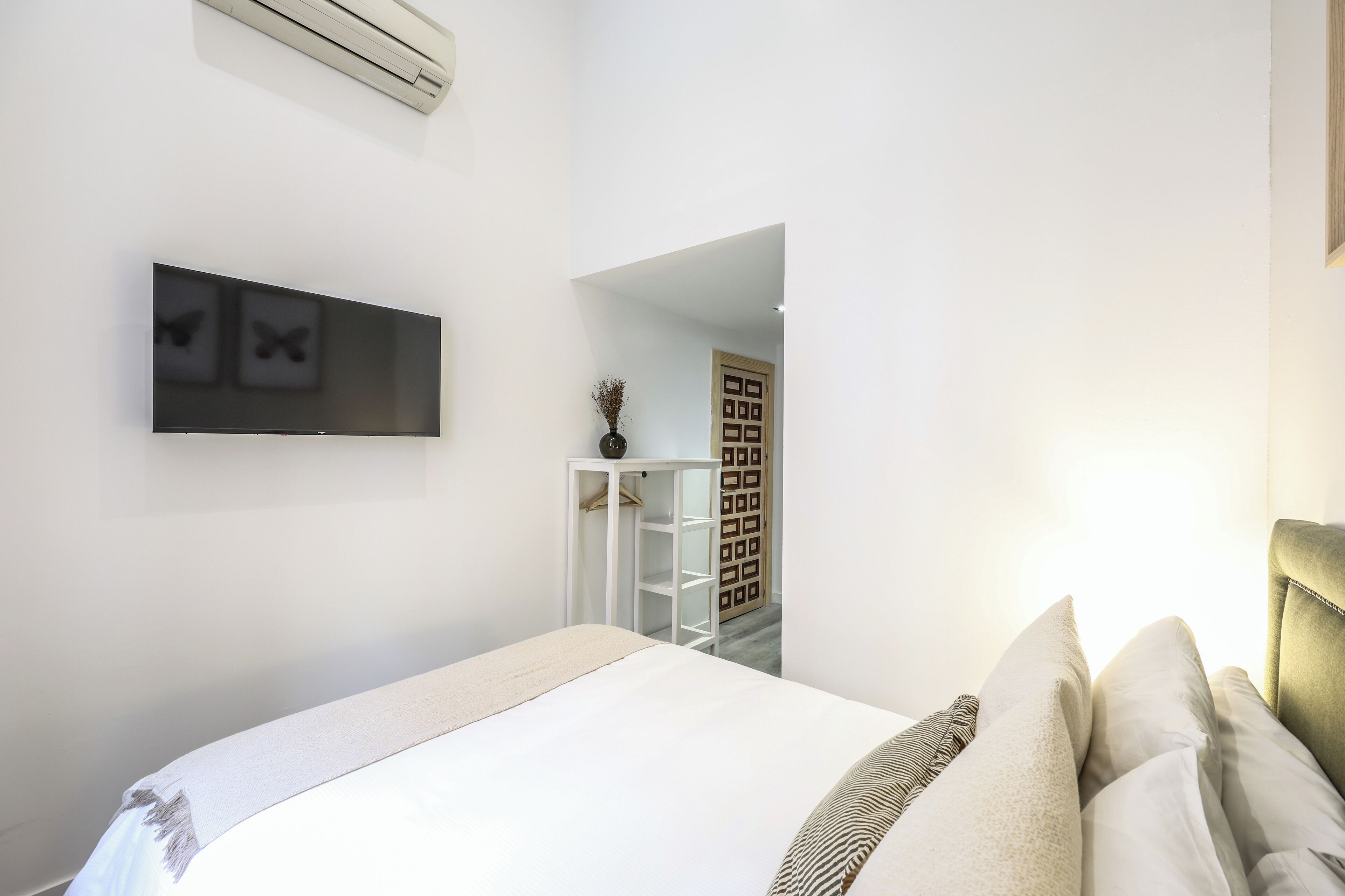 Una camera da letto con un letto, una TV fissata al muro e un armadio.