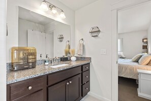 Une salle de bain moderne avec un grand miroir, des meubles sombres et un comptoir en granit.