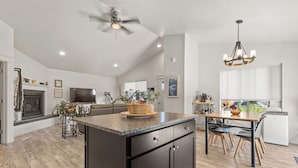 A spacious kitchen with a central island, dark cabinetry, and a ceiling fan.