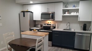 A modern kitchen with white cabinets, a microwave, a stove, a sink, and a dishwasher. - Home away from Home. Recent secure building. Completely equipped kitchen. (Whitehorse)