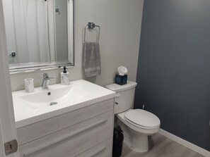 Ein Badezimmer mit Waschbecken, Spiegel, Handtuch und Toilette.
