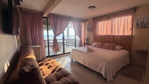 A bedroom with a bed, a sofa, a TV, and a view of the sea. - Oasis Suite with Ocean View Breakfast Included.  AcapulcoDiamante a (acapulco de juarez)
