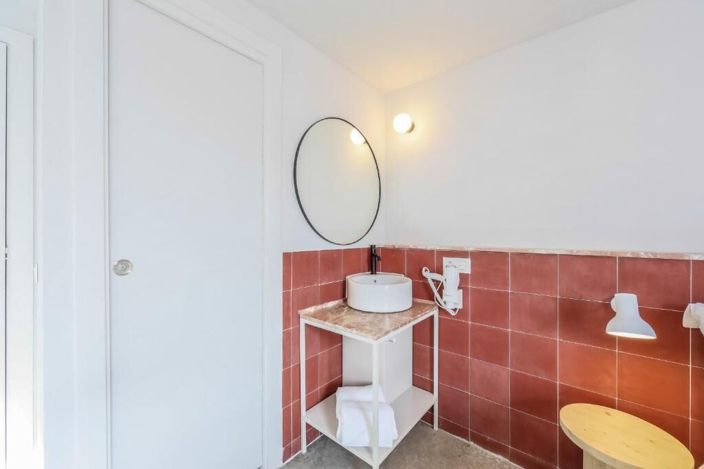 A bathroom with a white sink, a mirror, and a toilet.