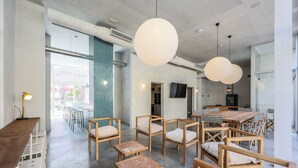 Et moderne interiør med et langt træbord, stole, store, hængende sfæriske lamper og en beton gulv.