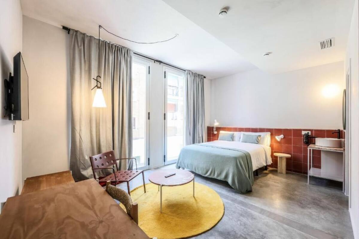 Une chambre d’hôtel comprenant un lit, un bureau, une chaise, une petite table et un téléviseur.