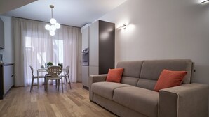 Een moderne woonkamer met een bank, een eettafel met stoelen en een keuken met een oven.