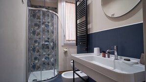 Een badkamer met een douche, toilet, wastafel en een spiegel.