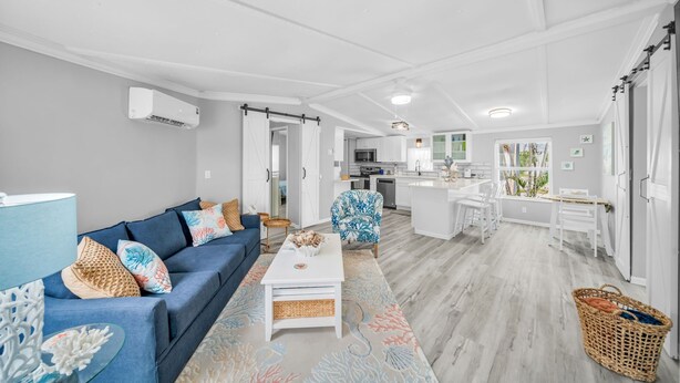 Ein modernes Wohnzimmer mit einem blauen Sofa, einem weißen Couchtisch und einer Küchenzeile im Hintergrund.