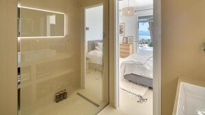 A modern bathroom with a glass shower enclosure, a large mirror, and a vanity.