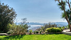 A landscaped garden with a view of a city and mountains in the distance.