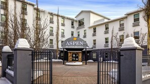 A hotel entrance with a gated driveway, a sign reading 'Aspen Suites Hotel,' and a building with multiple windows and balconies. - Aspen Suites Hotel Anchorage Downtown (Anchorage)