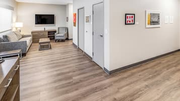 Una sala de estar moderna con un televisor de pantalla plana, un sofá gris, una mesa de centro de madera y un sillón gris.