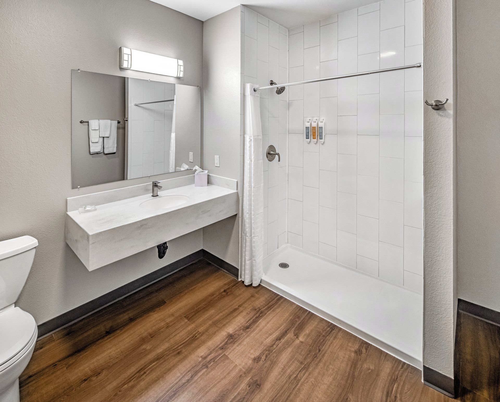 A modern bathroom with a white sink, mirror, and shower.