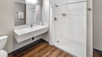 A modern bathroom with a white sink, mirror, and shower.