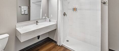 A modern bathroom with a white sink, mirror, and shower.