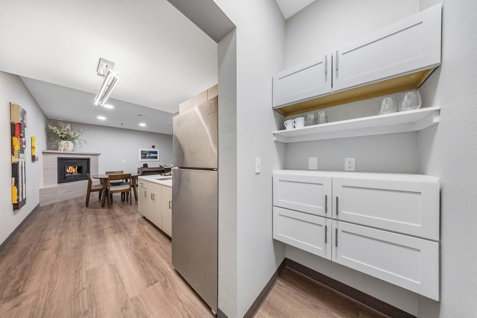 A modern kitchen with white cabinetry, a built-in oven, and a dining area with a wooden table and chairs.
