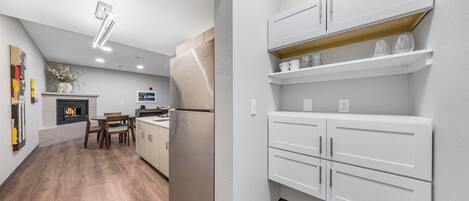 A modern kitchen with white cabinetry, a built-in oven, and a dining area with a wooden table and chairs.