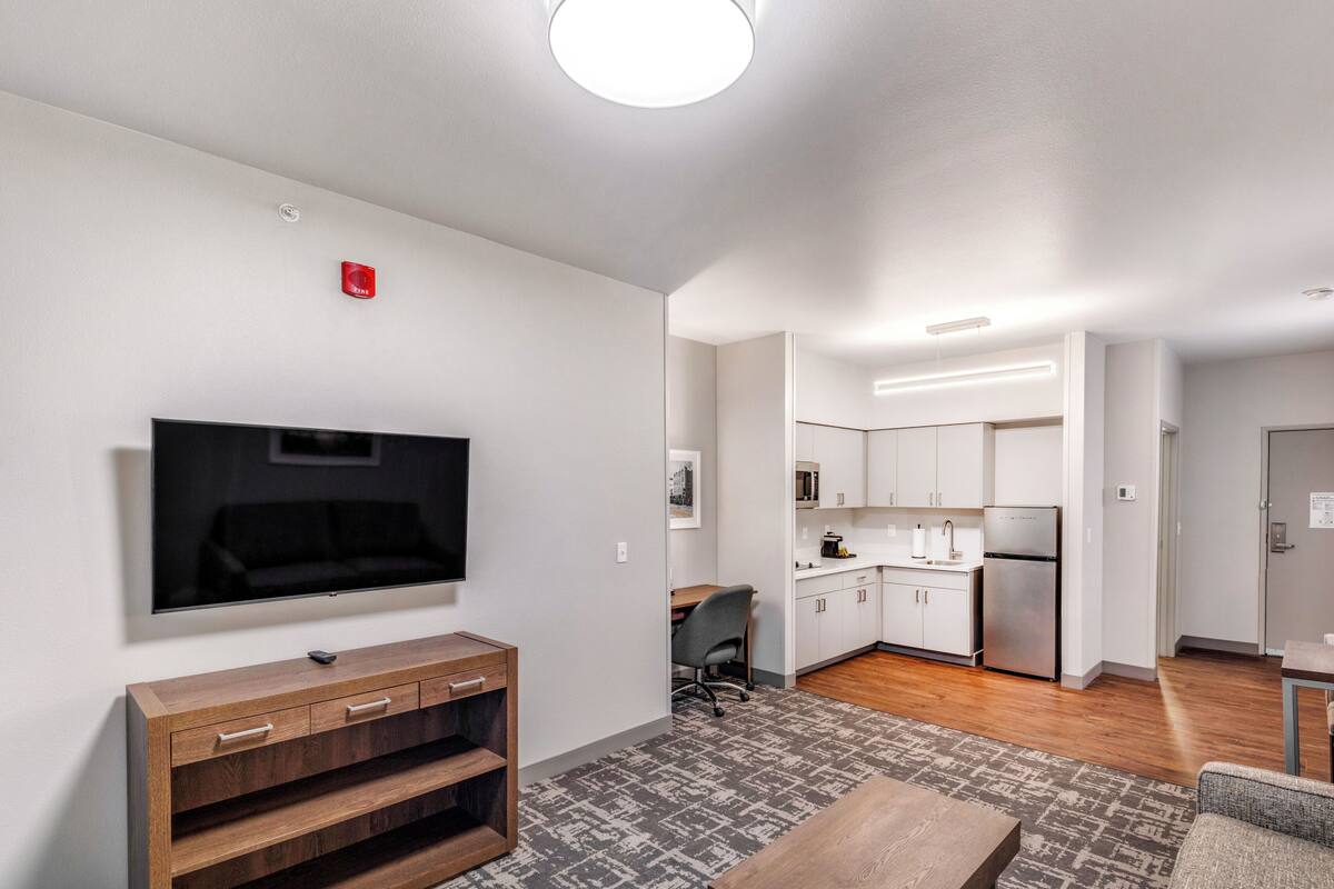 Ein modernes Wohnzimmer mit Flachbildfernseher, einer Holz-Unterhaltungseinheit und grauen gepolsterten Sofas.