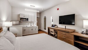 A hotel room with a bed, a desk, a TV, a microwave, and a bathroom. - Aspen Suites Hotel Anchorage Downtown (Anchorage)