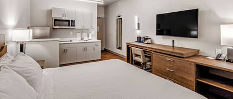 Une chambre d’hôtel équipée d’un lit, d’un bureau, d’une télévision, d’un four à micro-ondes et d’une salle de bain.