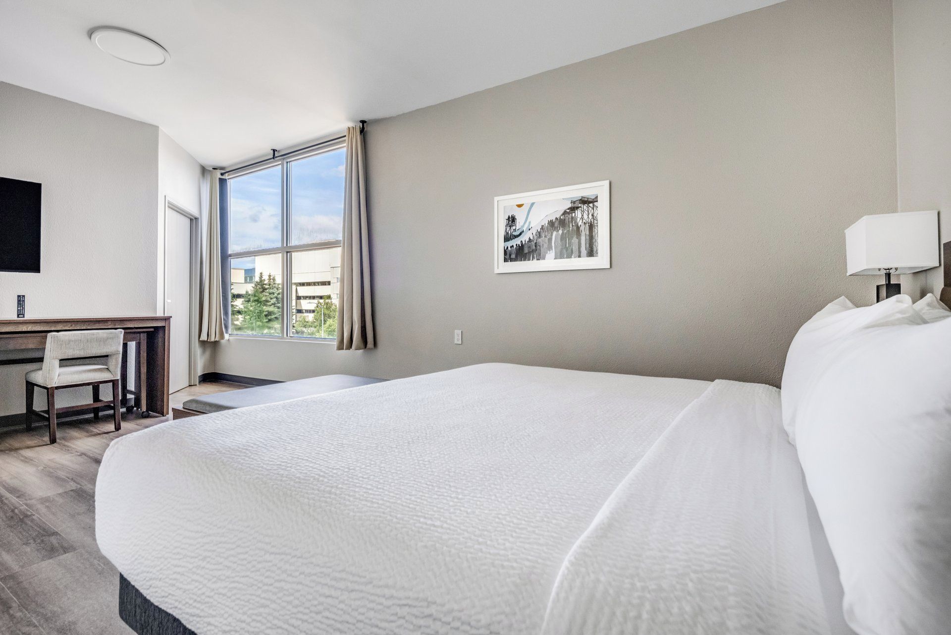 Una habitación de hotel con una cama grande, un escritorio y una silla.
