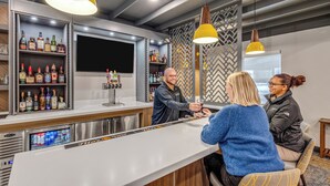 A bar area with a counter, shelves of liquor bottles, and hanging pendant lights. - Aspen Suites Hotel Anchorage Downtown (Anchorage)