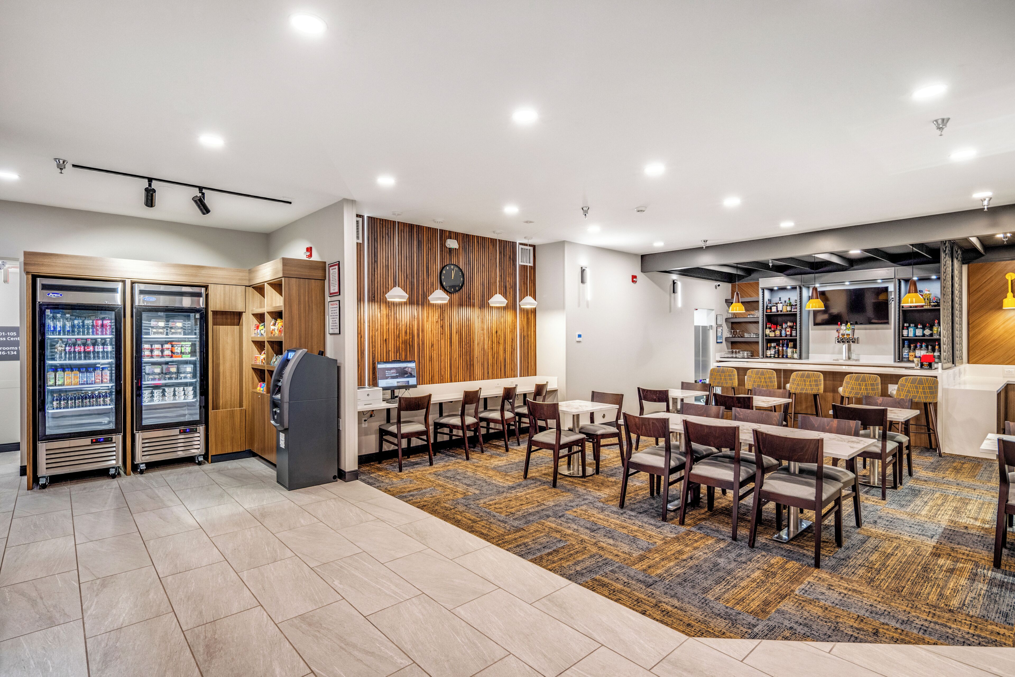 A hotel lobby with seating areas, a bar, and vending machines.