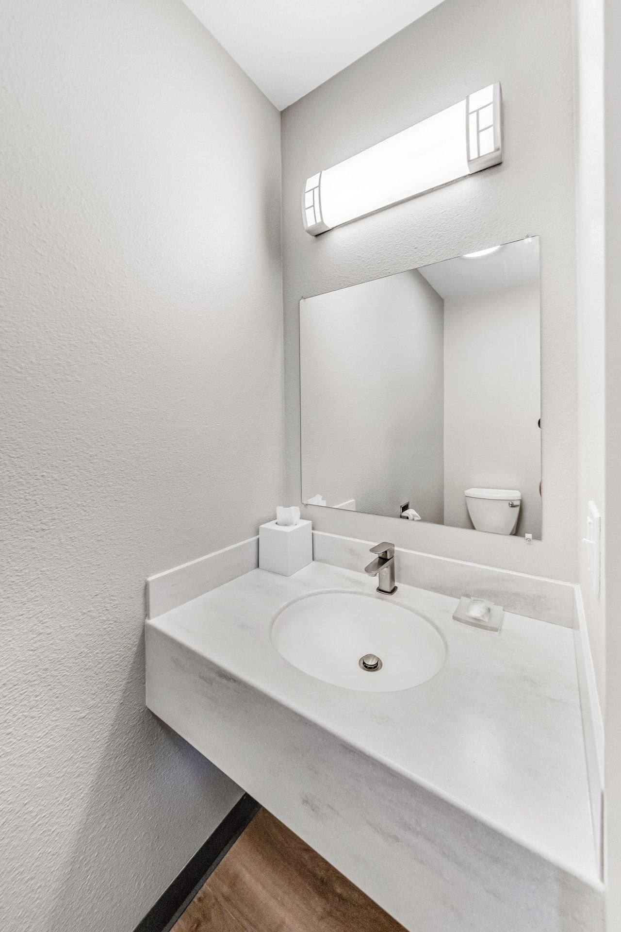 Une salle de bain avec un lavabo blanc, un miroir et des toilettes.