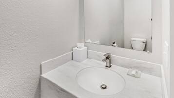 Une salle de bain avec un lavabo blanc, un miroir et des toilettes.