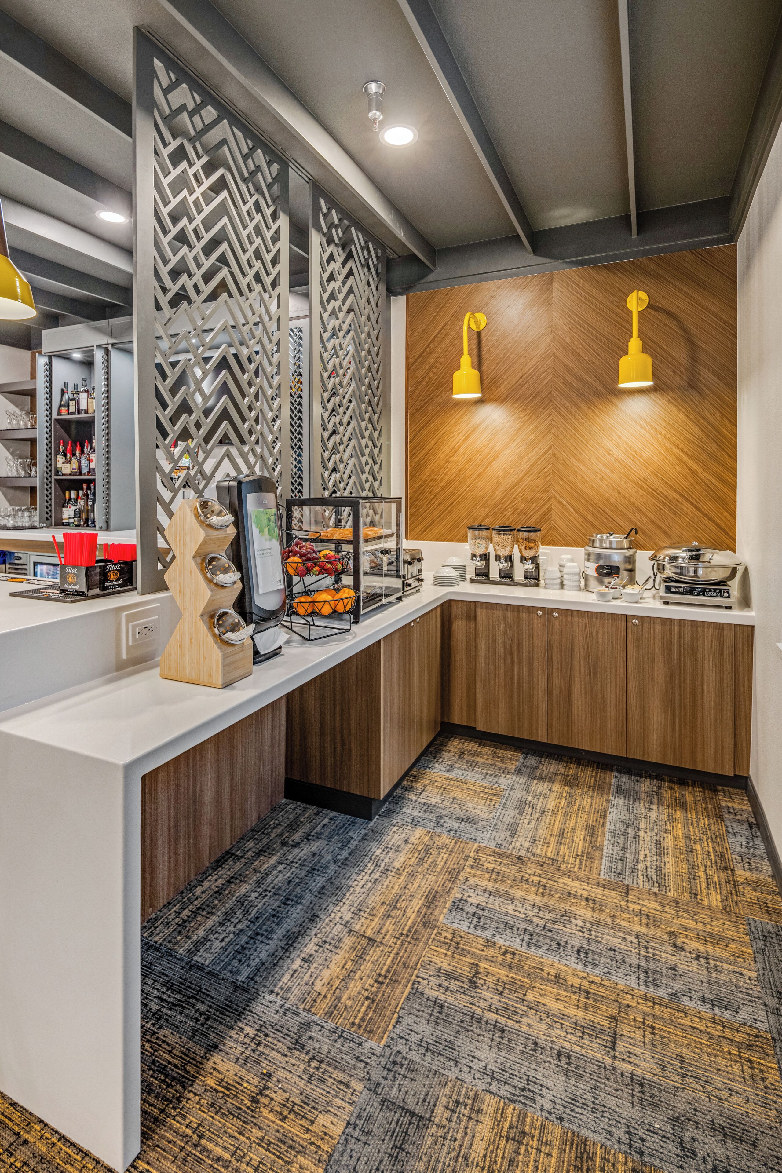 Een moderne hotel receptie met een balie, een koffiehoek en een patroonmuur.