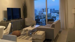 A modern living room with a large window, a flat-screen TV, and a sofa.