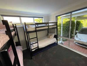 A room with bunk beds, a large window, and a view of a car outside.