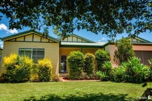 A two-story house with a green roof, a front porch, and a well-maintained lawn.