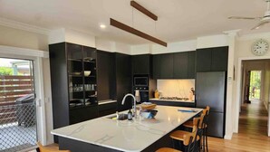 Une cuisine moderne dotée d’un îlot central, de tabourets de bar et de meubles de rangement aux couleurs sombres.