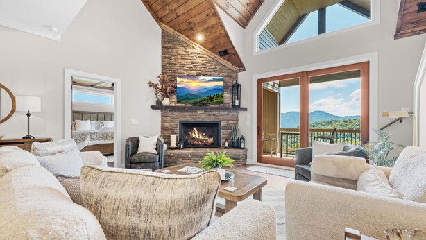 A spacious living room with a stone fireplace, comfortable seating, and a view of the outdoors.