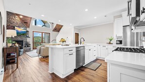 A modern kitchen with white cabinetry, a stainless steel range, and a large island.