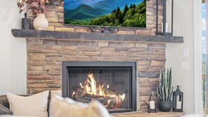 A living room with a stone fireplace, a television mounted above it, and a sofa with cushions.