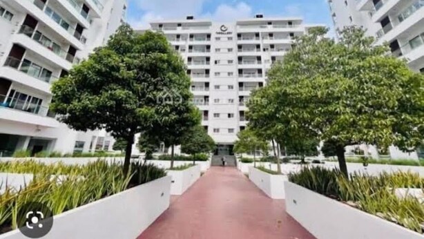 Un moderno edificio residenziale con un ingresso centrale, immerso nel verde e con un viale rosso.