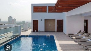 Una piscina sul tetto con lettini e vista sulla città.