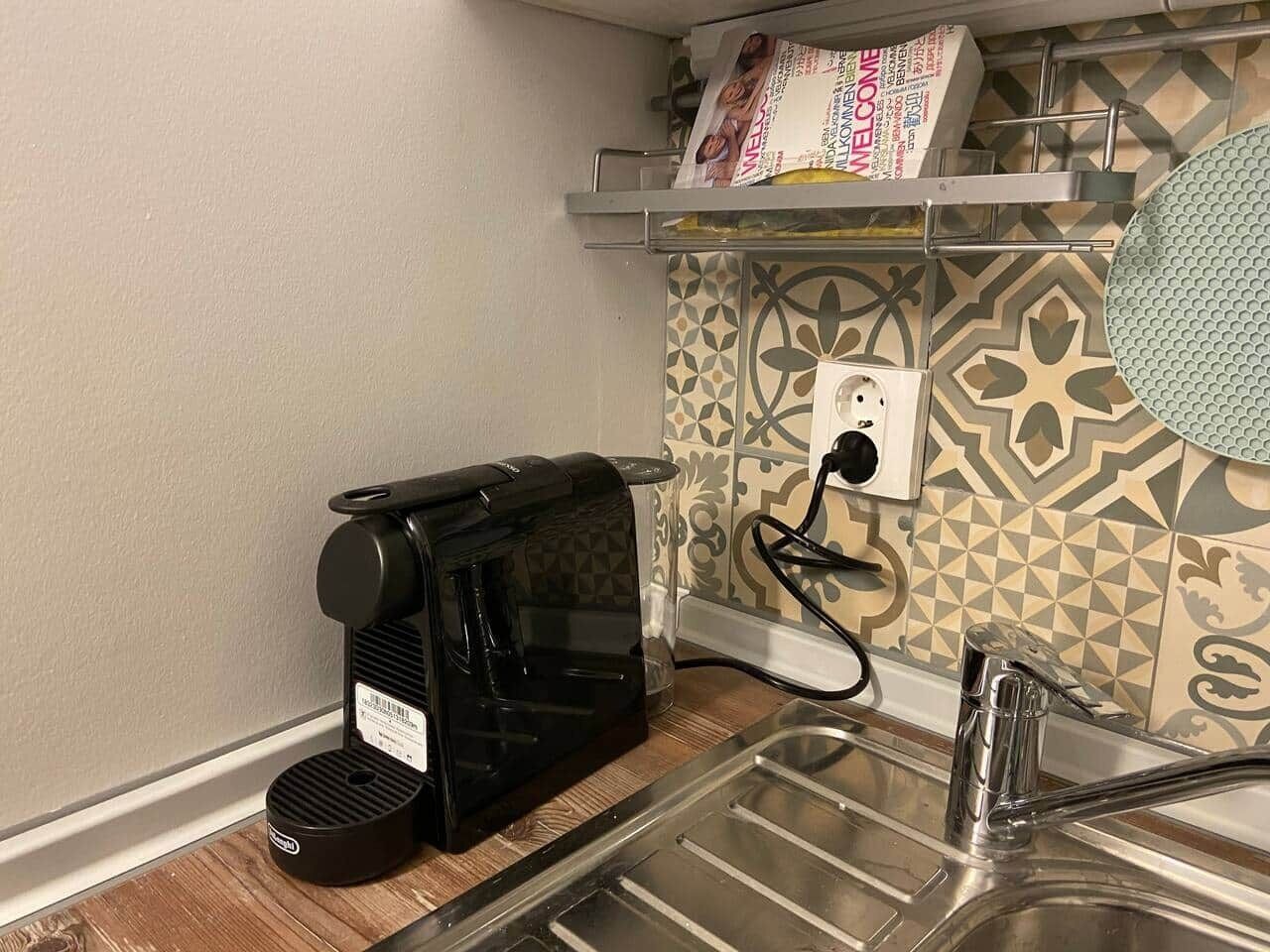 A kitchen with a coffee maker, a sink, and a patterned backsplash.