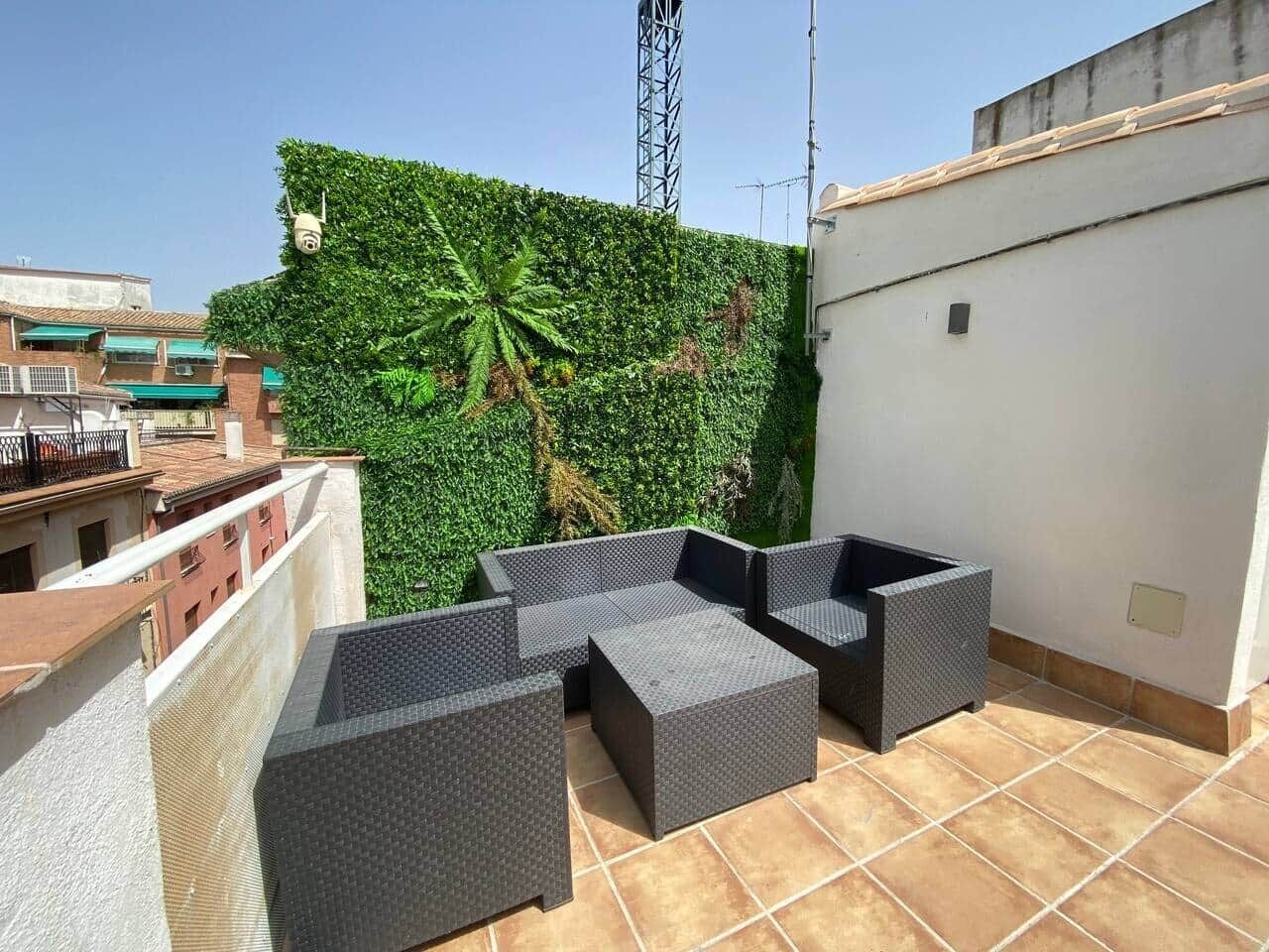 Una terrazza sul tetto con un muro verde, una torre metallica e un edificio bianco.