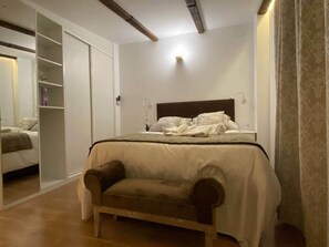 Un dormitorio con cama, mesita de noche, armario y una silla.