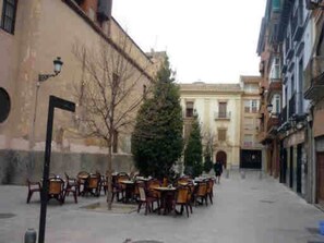Una calle estrecha con mesas al aire libre, un árbol de Navidad y edificios a ambos lados.