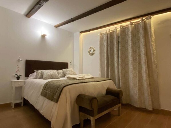 Un dormitorio con cama, mesita de noche y un banco.