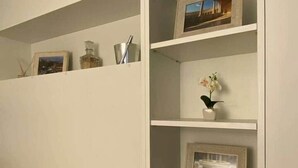 A white shelving unit with various decorative items and framed pictures.