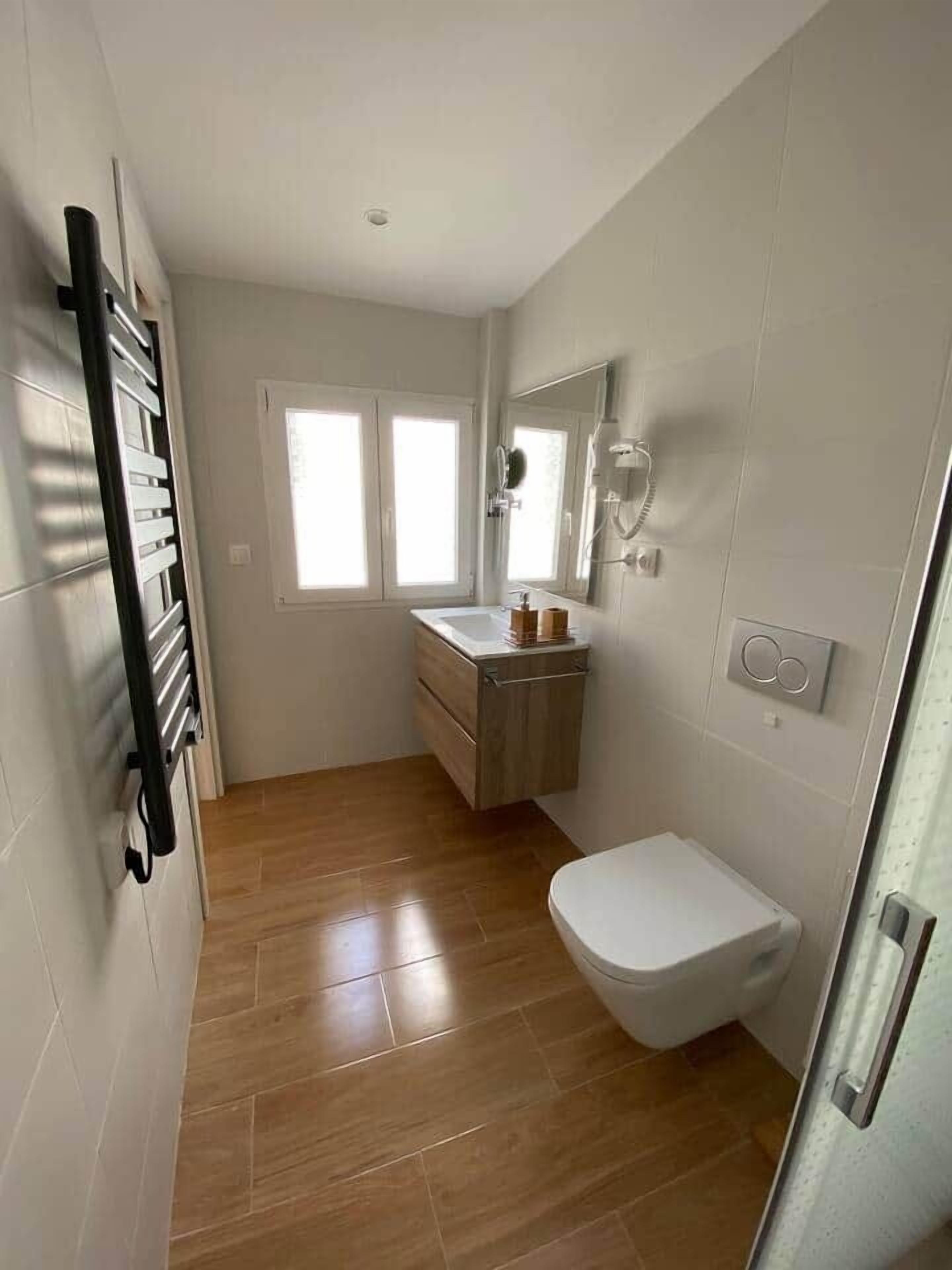 Un baño pequeño y moderno con inodoro, lavamanos y espejo.