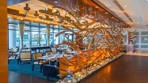 En moderne restaurant med en unik træskulptur i midten, store vinduer og moderne møbler.