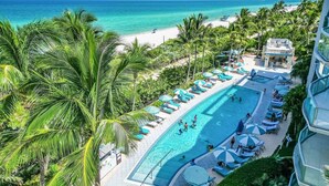 Et resort med swimmingpool, strand og palmer.